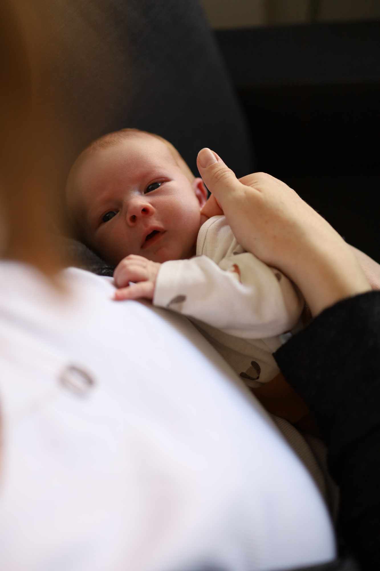 Frau streichelt ihr Baby über die Wange, Baby sieht Frau dabei an.